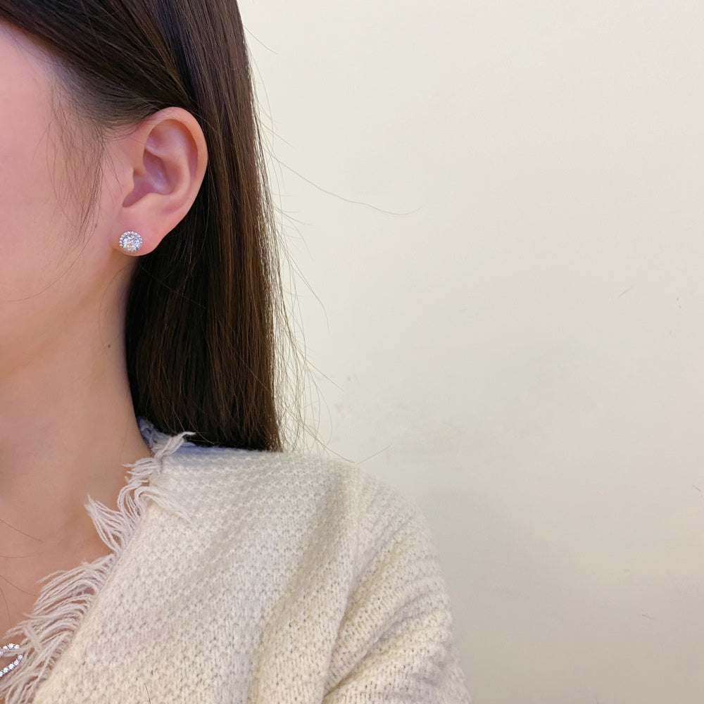 A rhodium-plated stud earring with a clear, zirconia main stone in a small circle design.