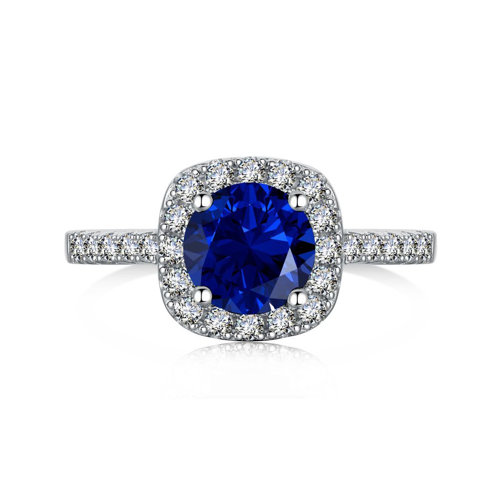 An elegant sterling silver ring featuring a round blue zircon stone with smaller clear stones around it, showcasing an inspired design.