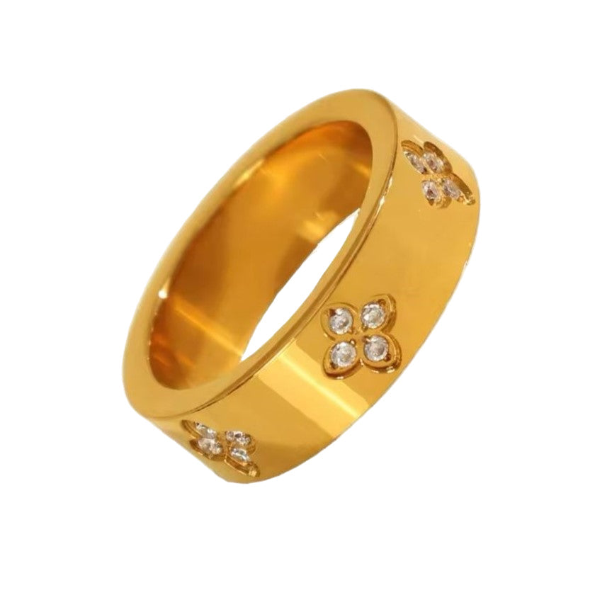 A gold-colored stainless steel ring with flower-shaped rhinestone accents on the top.