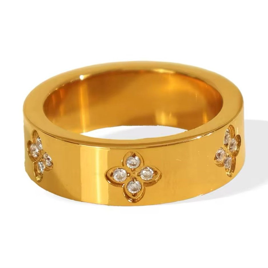 A gold-colored stainless steel ring with flower-shaped rhinestone accents on the top.