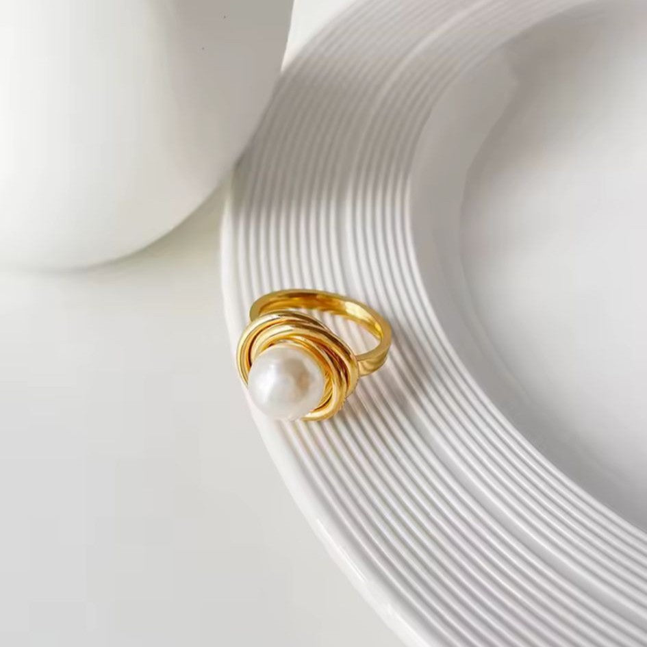 Gold ring with a pearl on a white ceramic plate