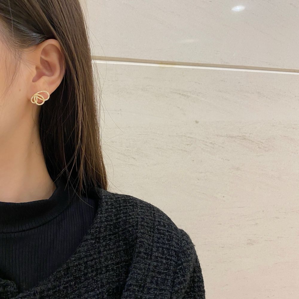 An 18K gold plated butterfly earring with cubic zirconia embellishments on a women's ear.