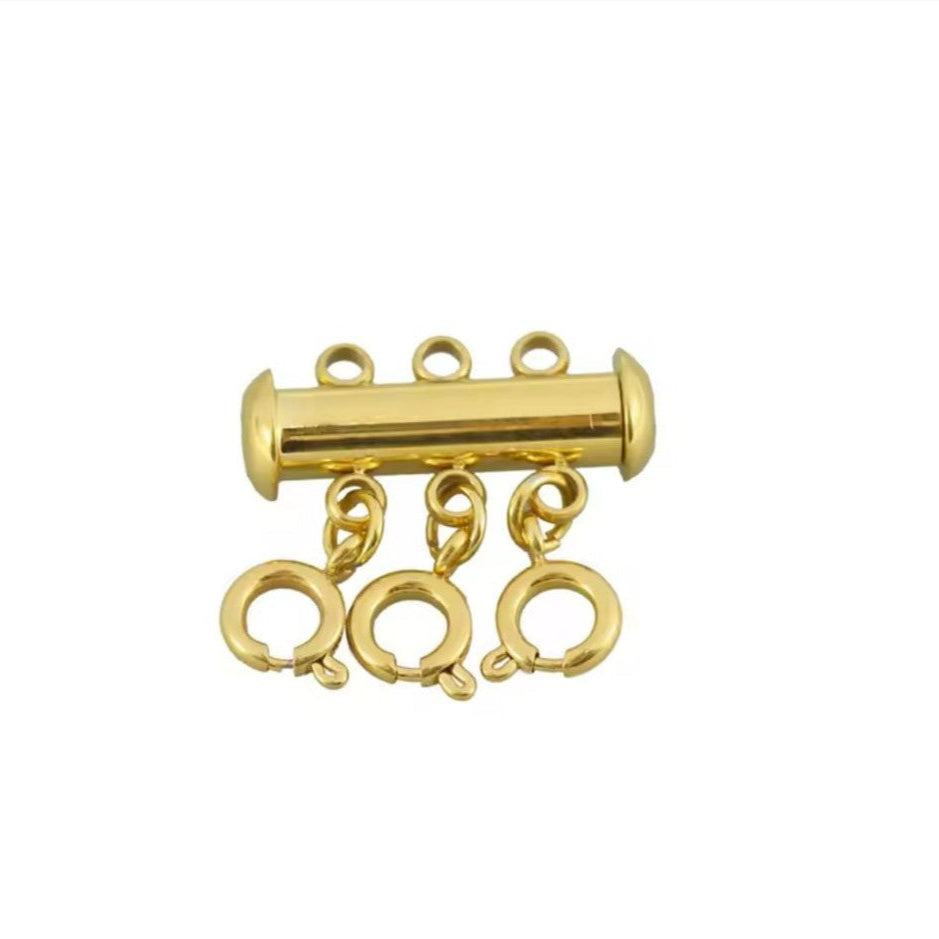 An 18K gold plated triple necklace layering clasp with a gold color option, featuring a cylindrical body with three looped chains extending from the bottom.