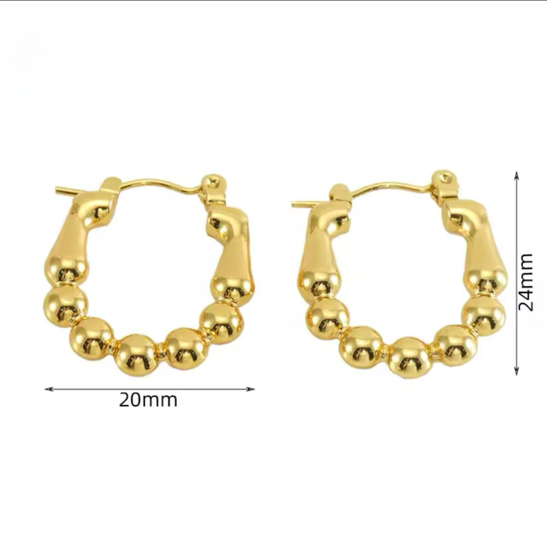 A pair of gold-colored Luxe Sphere Hoops crafted with high-quality materials displayed on white background.