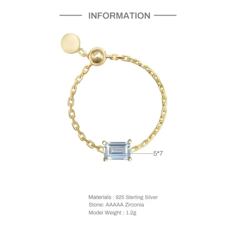 A gold chain ring with a clear gemstone on a white background