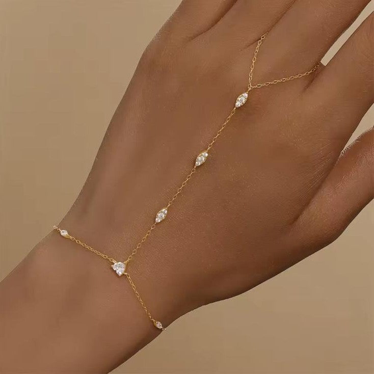 Gold chain bracelet with small diamonds on a wrist against a beige background