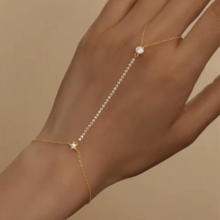 Gold chain bracelet with a diamond on a hand against a beige background