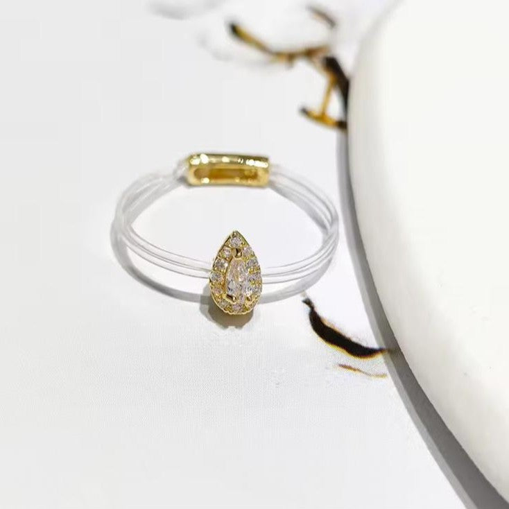 Pear-shaped yellow diamond ring on a clear stand with a white background