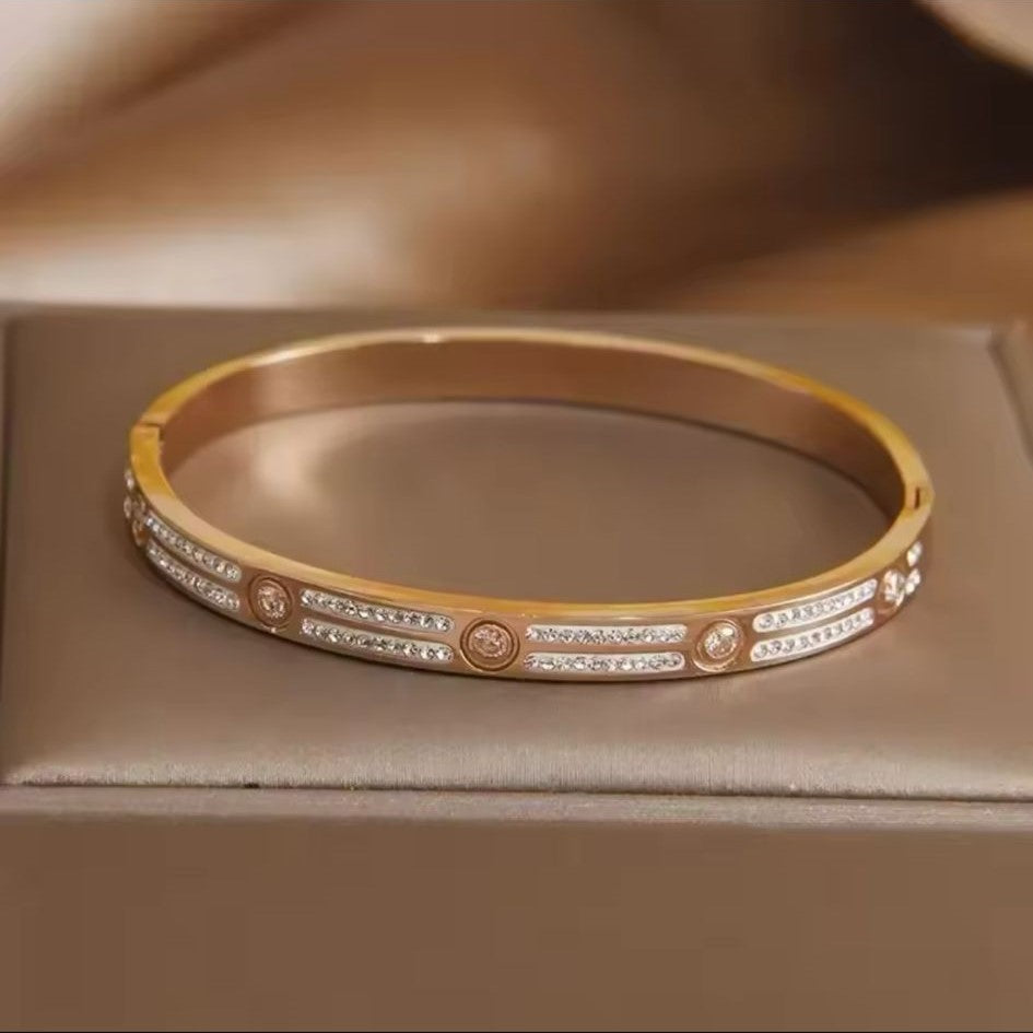 Gold bracelet with embedded stones on a neutral background
