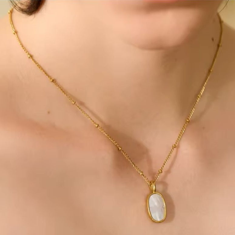 A Double-Sided Gold colored Natural Shell Cast Pendant Necklace in 18K Gold Plated presented on a women's neck.
