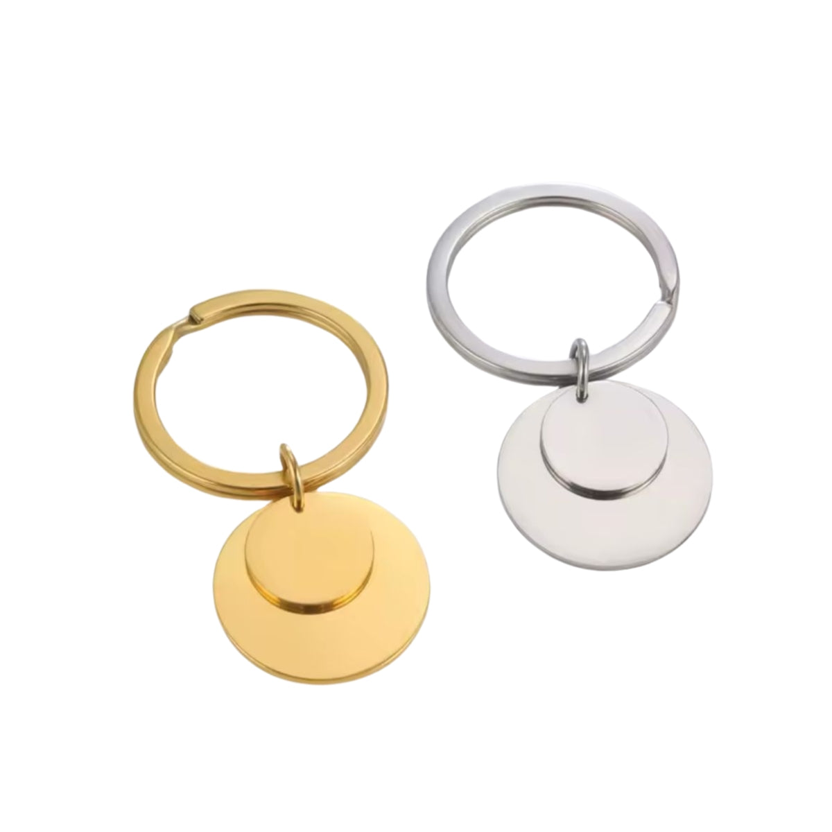 Two round engravable charms attached to a keyring, one in gold finish and the other in silver, displayed against a white background.
