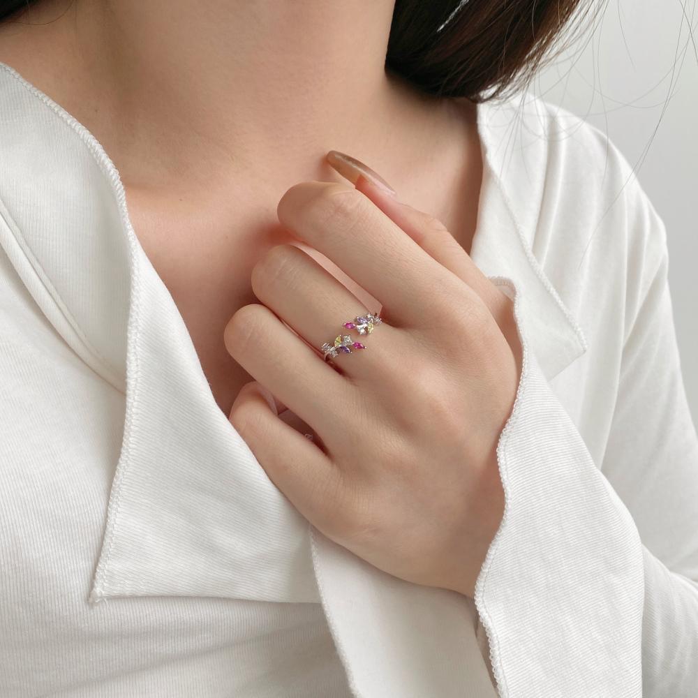 An adjustable silver ring featuring a floral design with multiple multicolored gemstones.