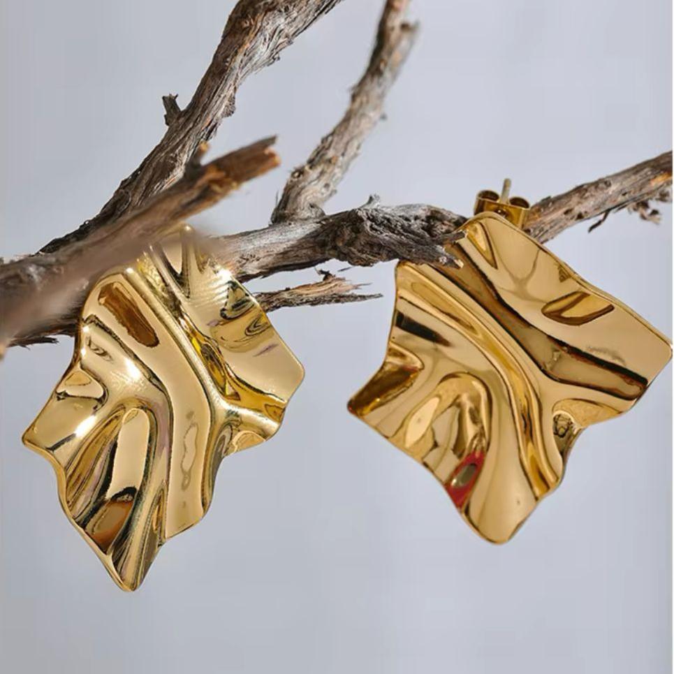 A pair of gold-colored textured earrings with a freeform ripple design.