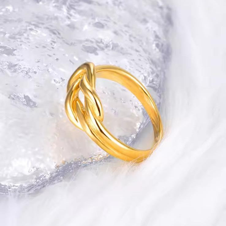 Gold ring with a knot design on a textured white background