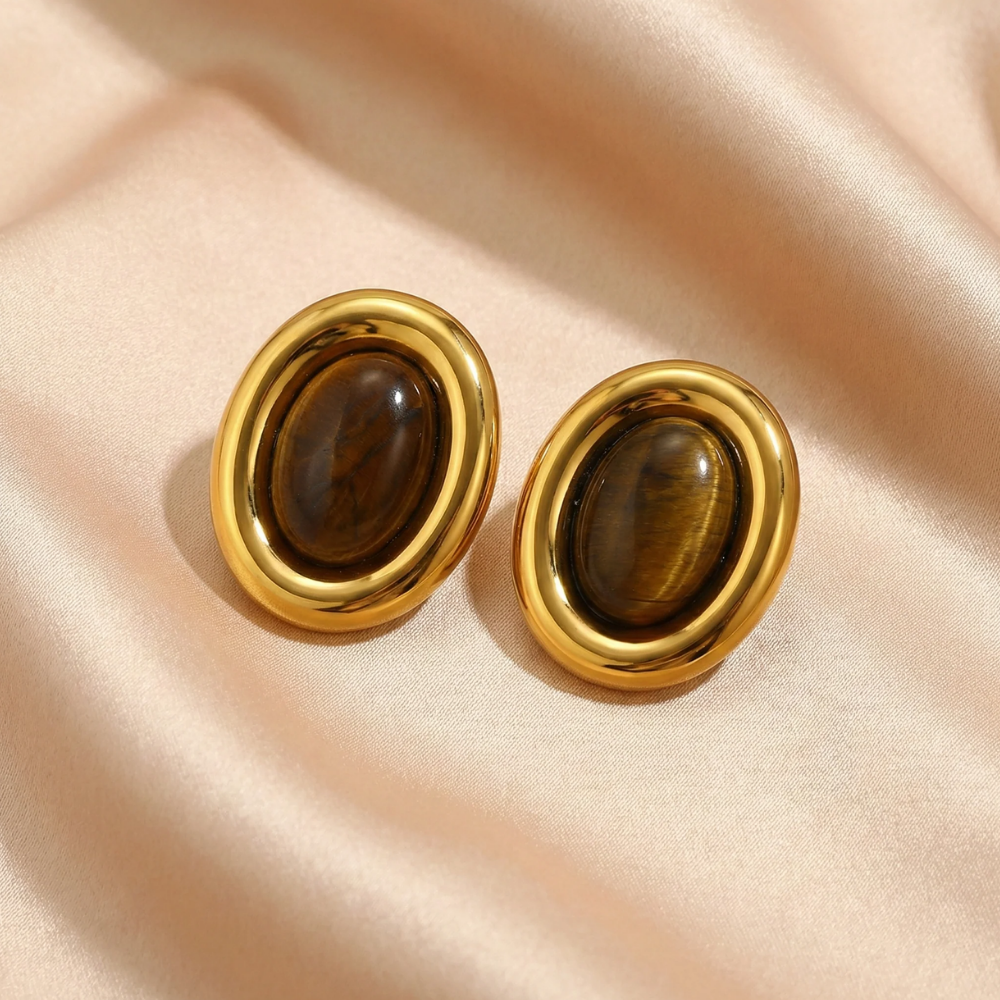 Pair of gold earrings with large natural stones on a fabric background