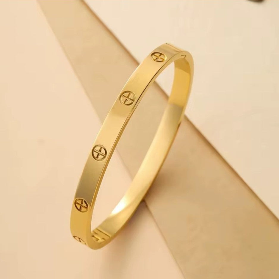Gold bracelet with engraved symbols on a beige background