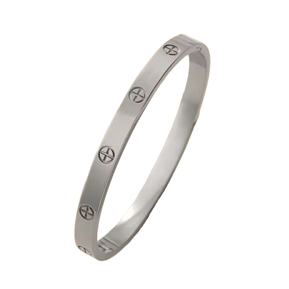 Silver bracelet with engraved symbols on a beige background