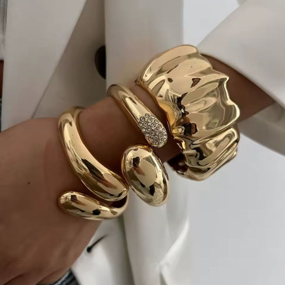 Gold bracelets on a wrist with a neutral background