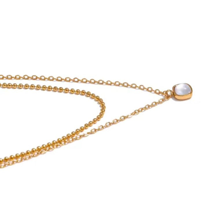 A gold-colored stainless steel necklace with a layered chain design and a square natural stone pendant.
