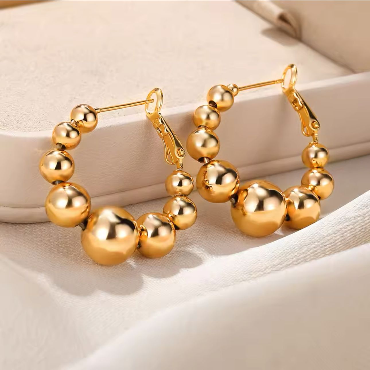 A pair of ornate beaded hoop earrings crafted from gold-plated stainless steel.