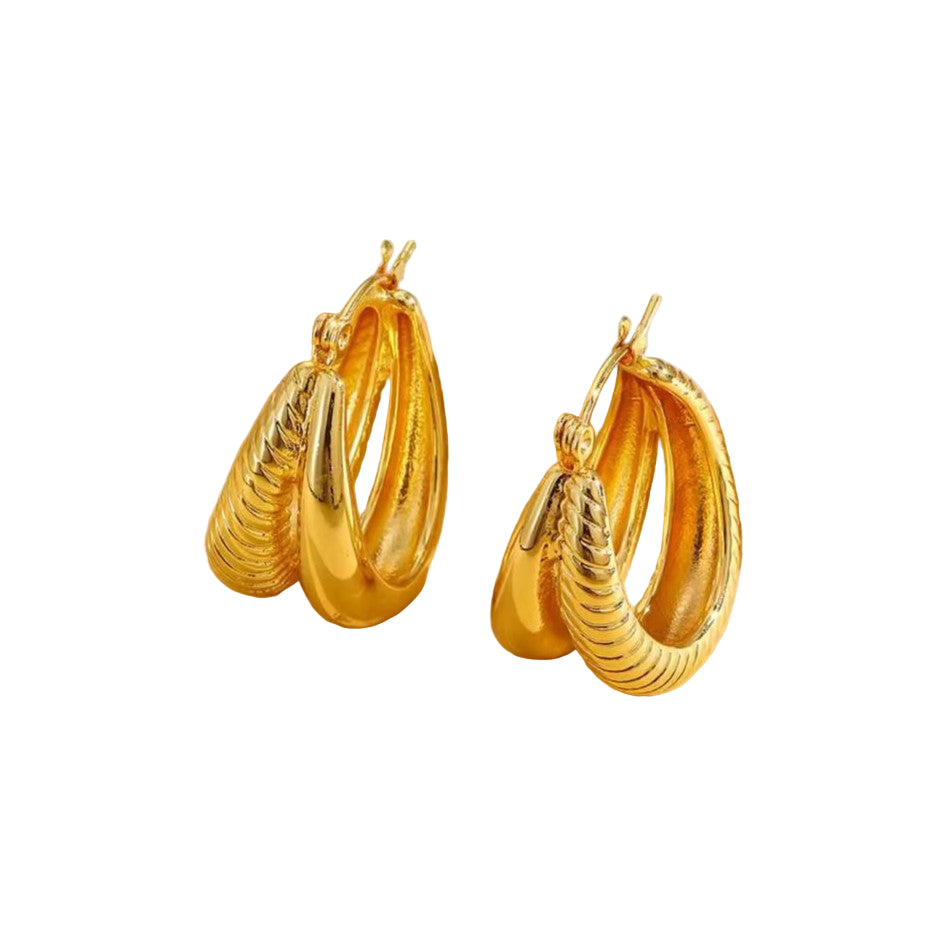 Gold hoop earrings on a textured beige surface