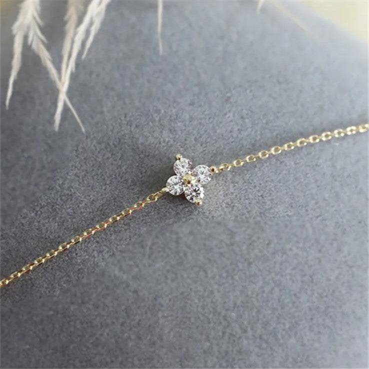 A close-up image of a small dainty bracelet with a single flower design. The bracelet is made of 925 sterling silver and appears in a gold tone.