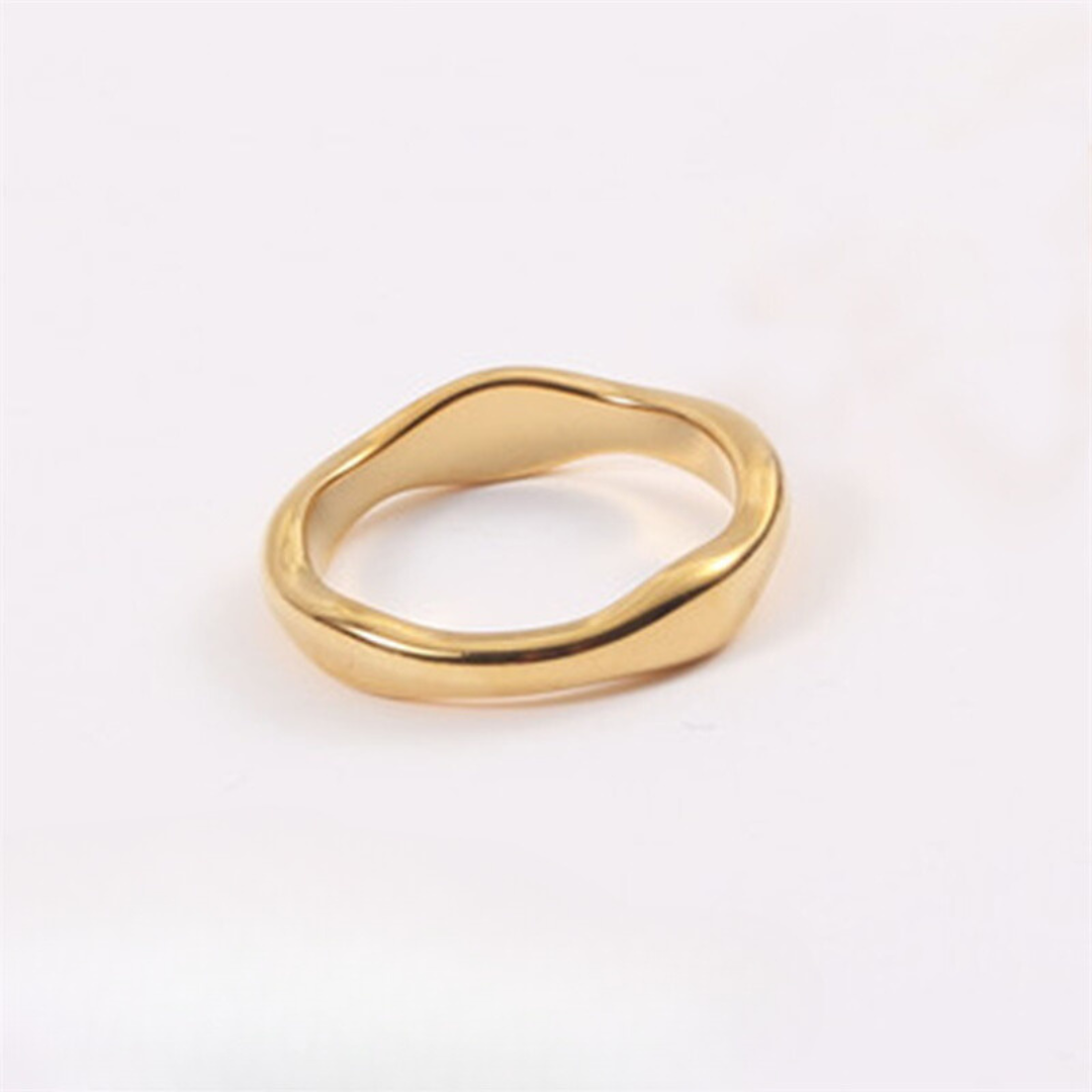 A gold-colored band ring with a wavy design, made from stainless steel, displayed on a plain background.