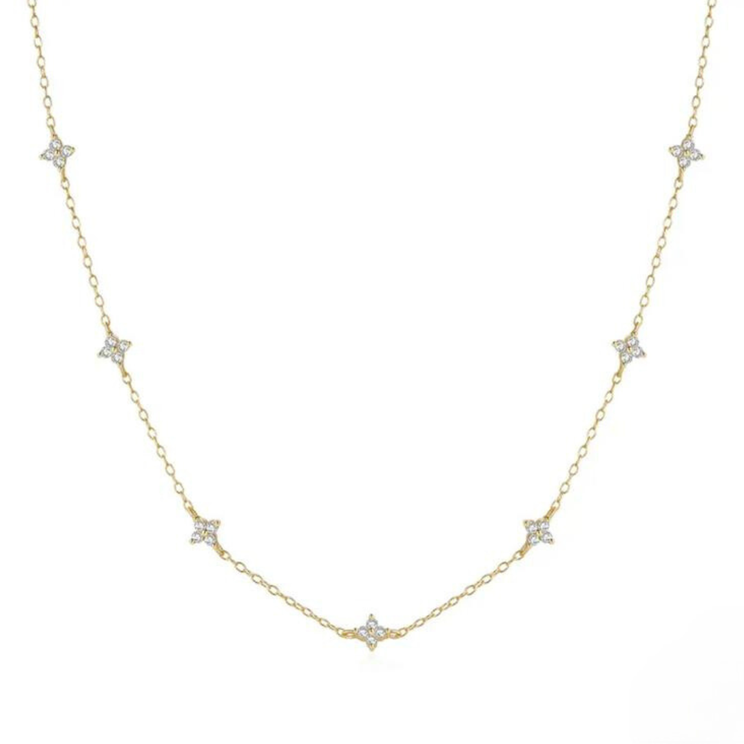 A sterling silver necklace featuring a series of small dainty flower-shaped pendants, with a gold color scheme.
