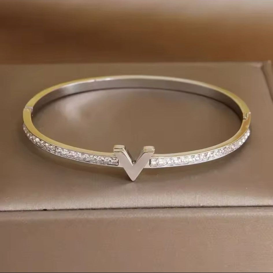 A silver stainless steel bracelet featuring a V-shaped pattern of inset stones, showcasing a sophisticated and elegant design.