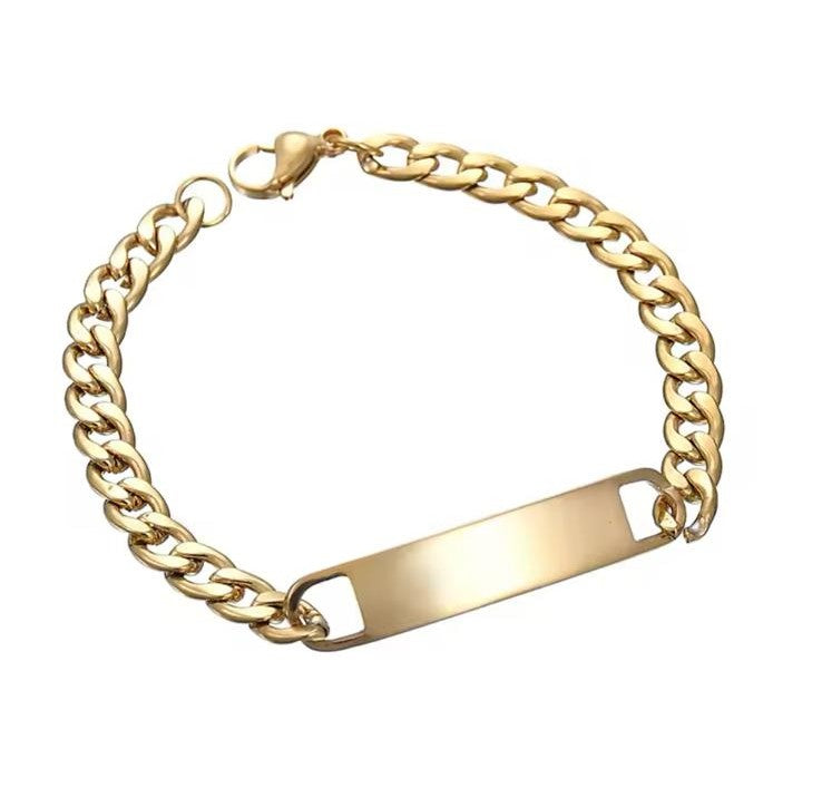A gold-colored stainless steel bracelet with a curb chain design and an engraved bar pendant in the center.