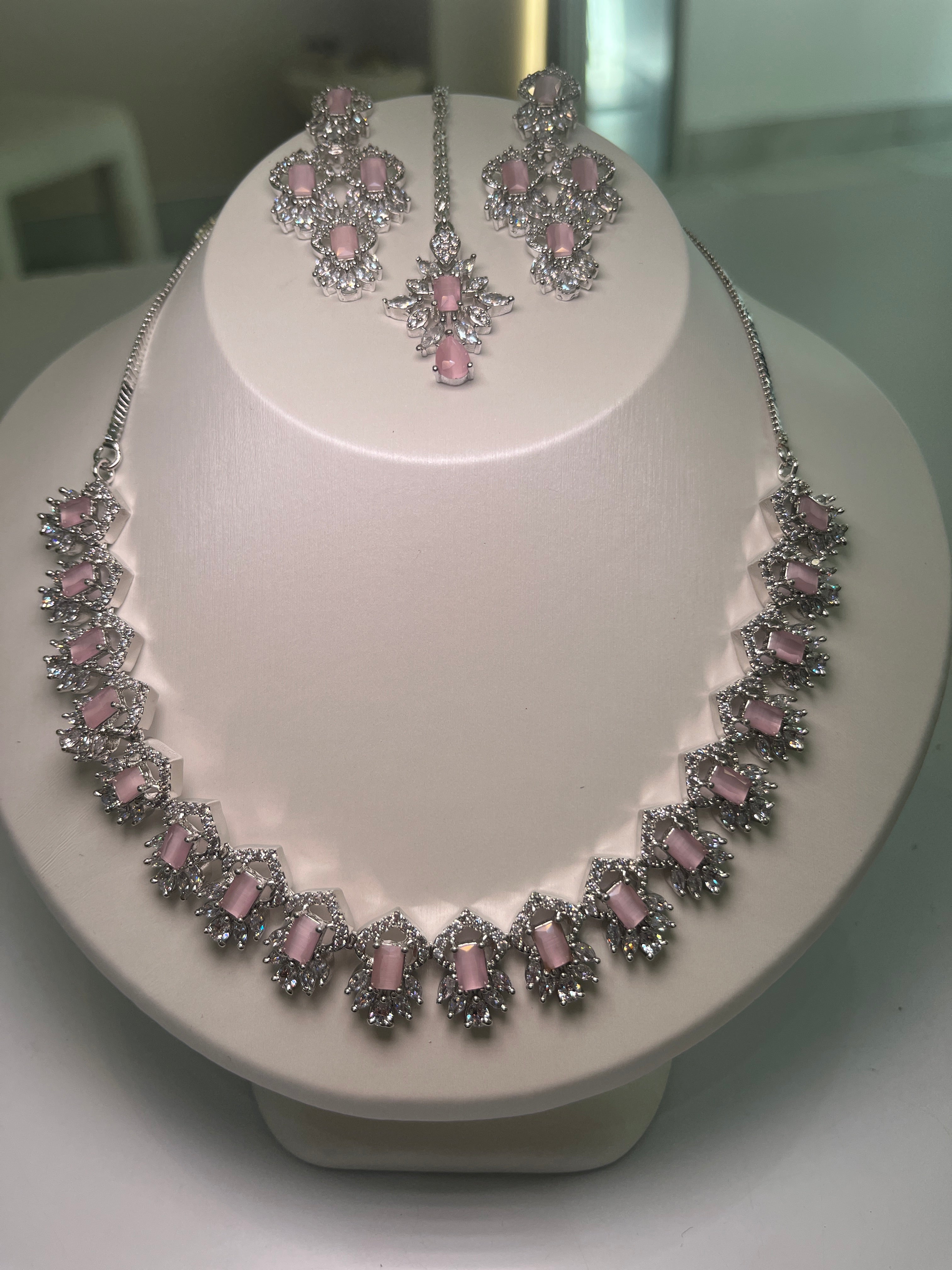 A necklace and earrings set with baguette-cut gemstones and brilliant crystals displayed on a mannequin.