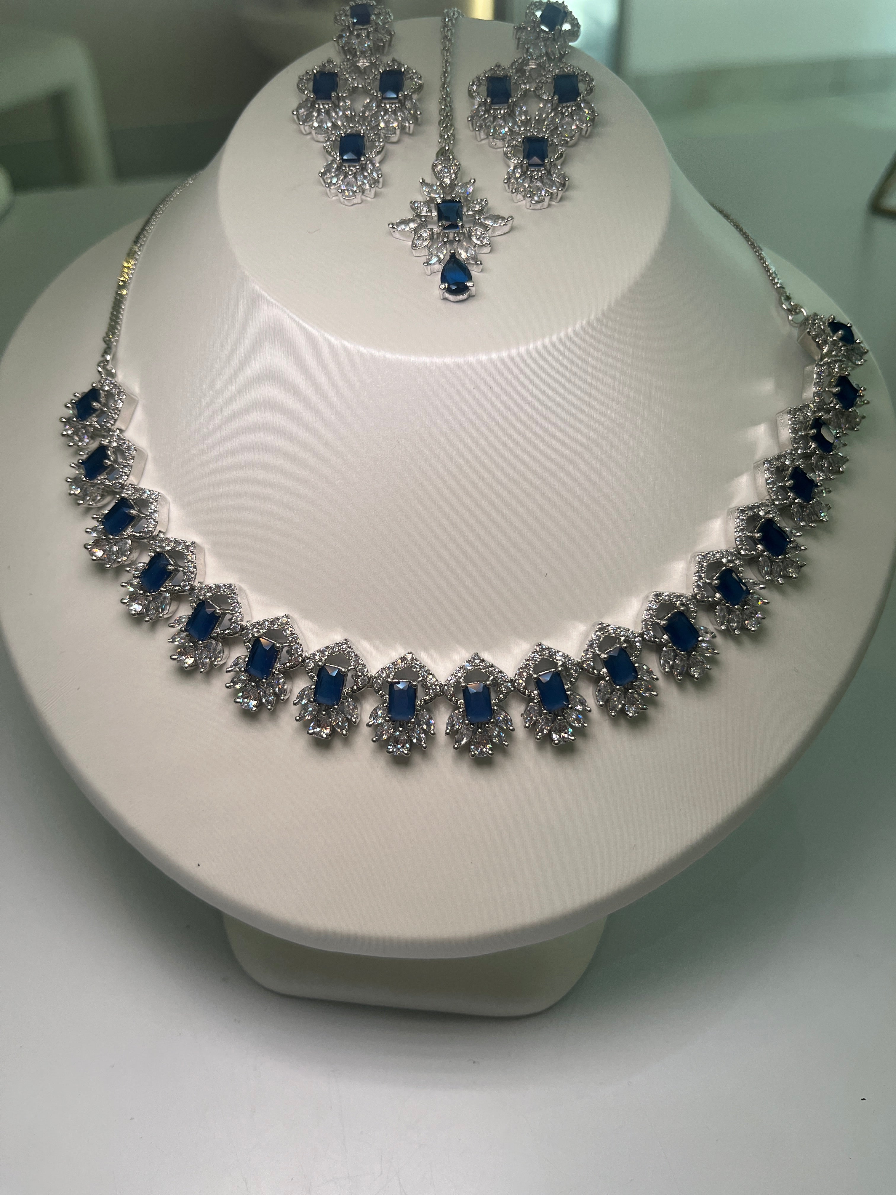 A necklace and earrings set with baguette-cut gemstones and brilliant crystals displayed on a mannequin.