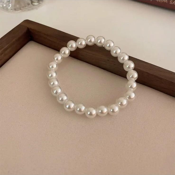 A bracelet made of luminous freshwater pearls displayed on a flat surface.