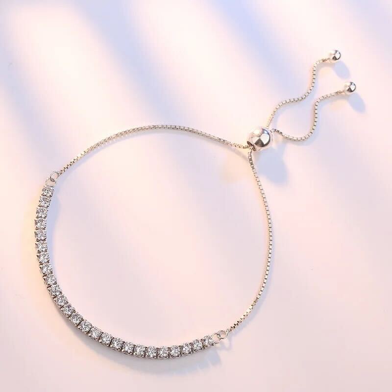 An adjustable silver bracelet with a row of sparkling stones, presented against a white background.