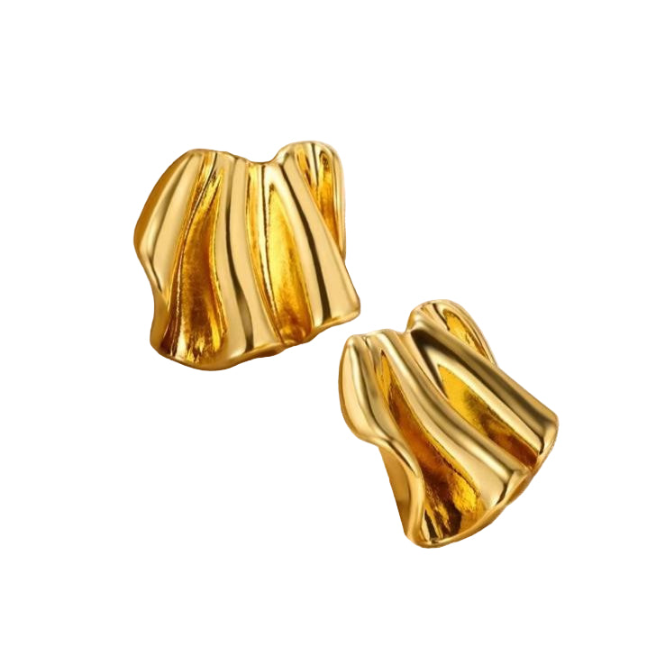 A pair of gold-colored, wave-shaped metal earrings resting on a beige surface.