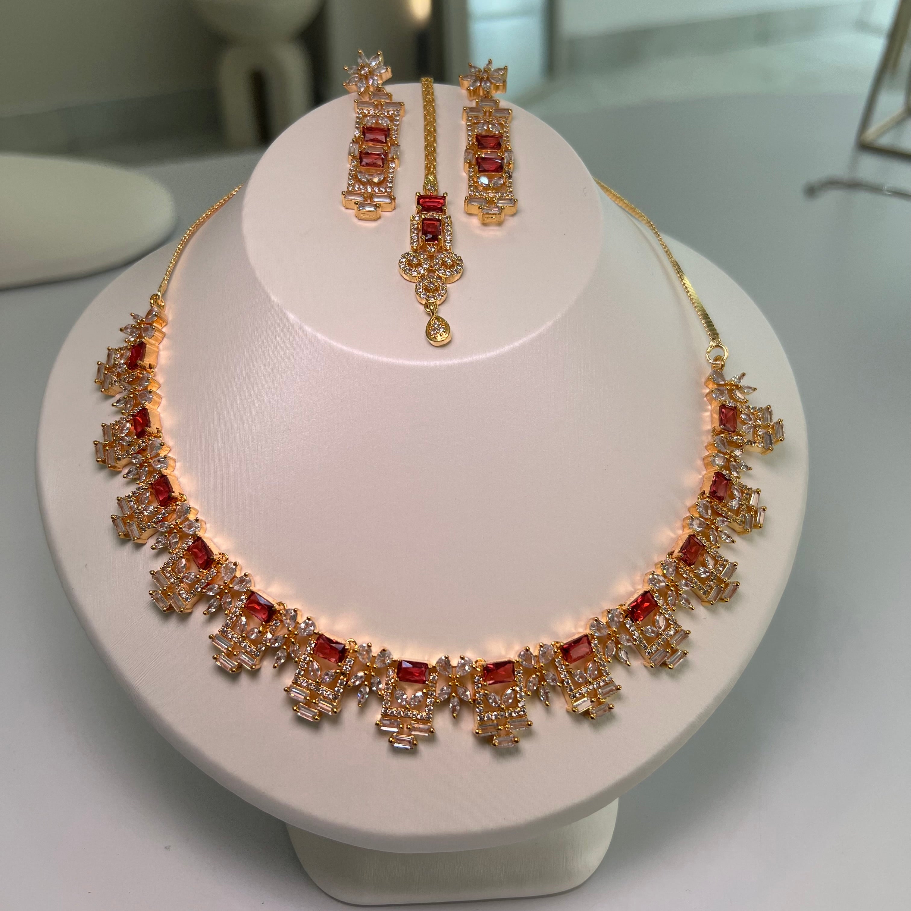 A gold-tone rectangle motif necklace with matching earrings displayed on a mannequin bust.