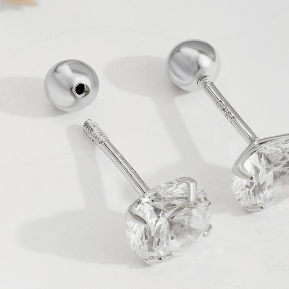 A pair of gold-plated barbell stud earrings with one stud earring featuring a clear, faceted gemstone on the end.