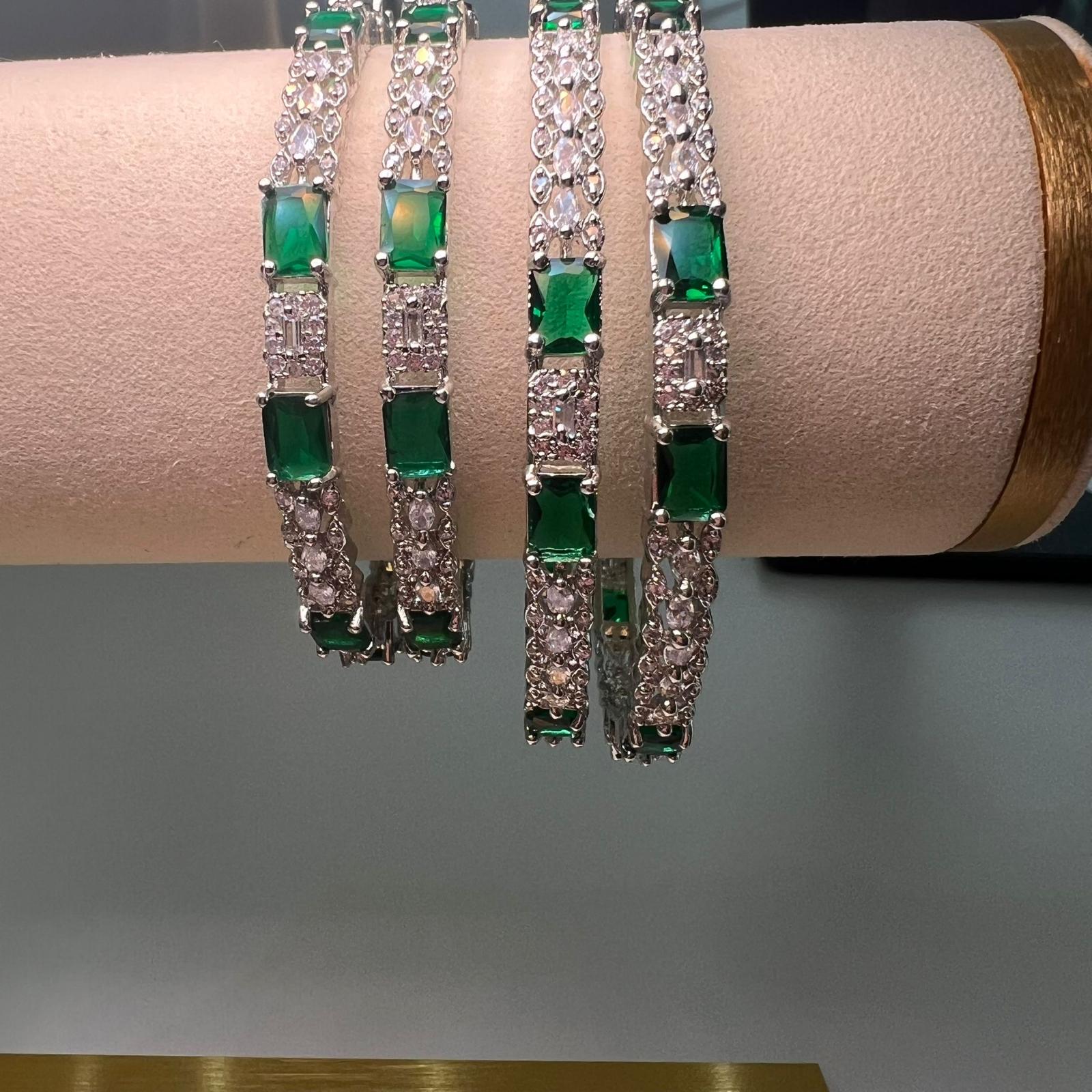 Set of green gemstone and diamond bracelets on a display stand.