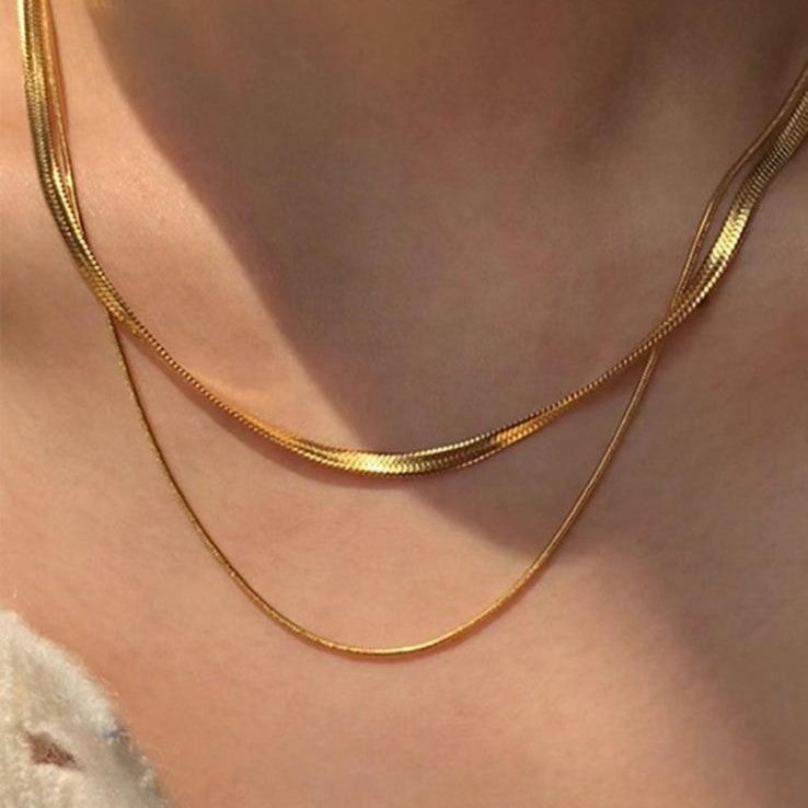 Two layered flat snake chain necklaces in gold tone, displayed against a white background.