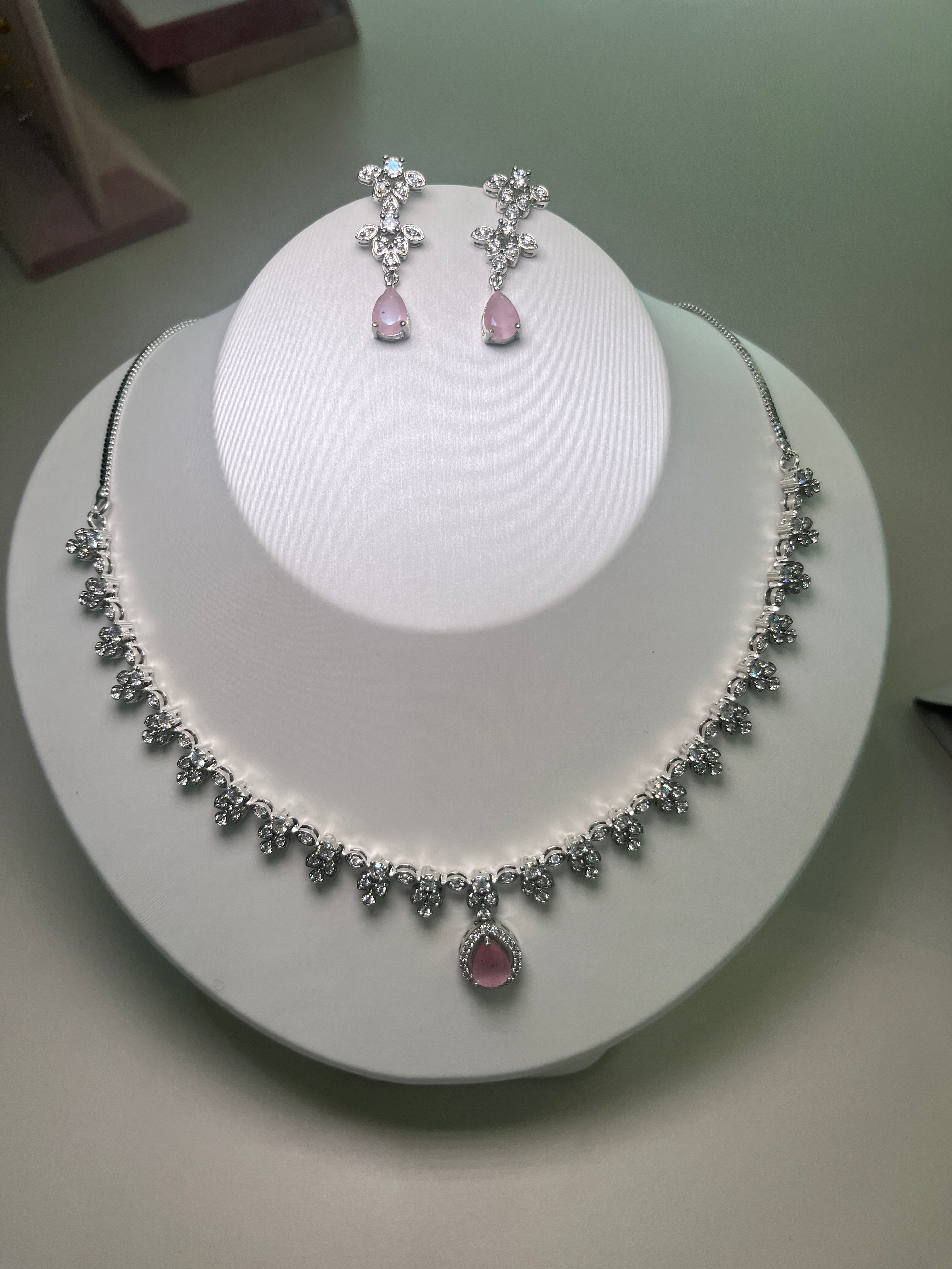 A necklace and earrings set featuring a teardrop-shaped gemstone centerpiece with a silver-tone finish, displayed on a mannequin bust.