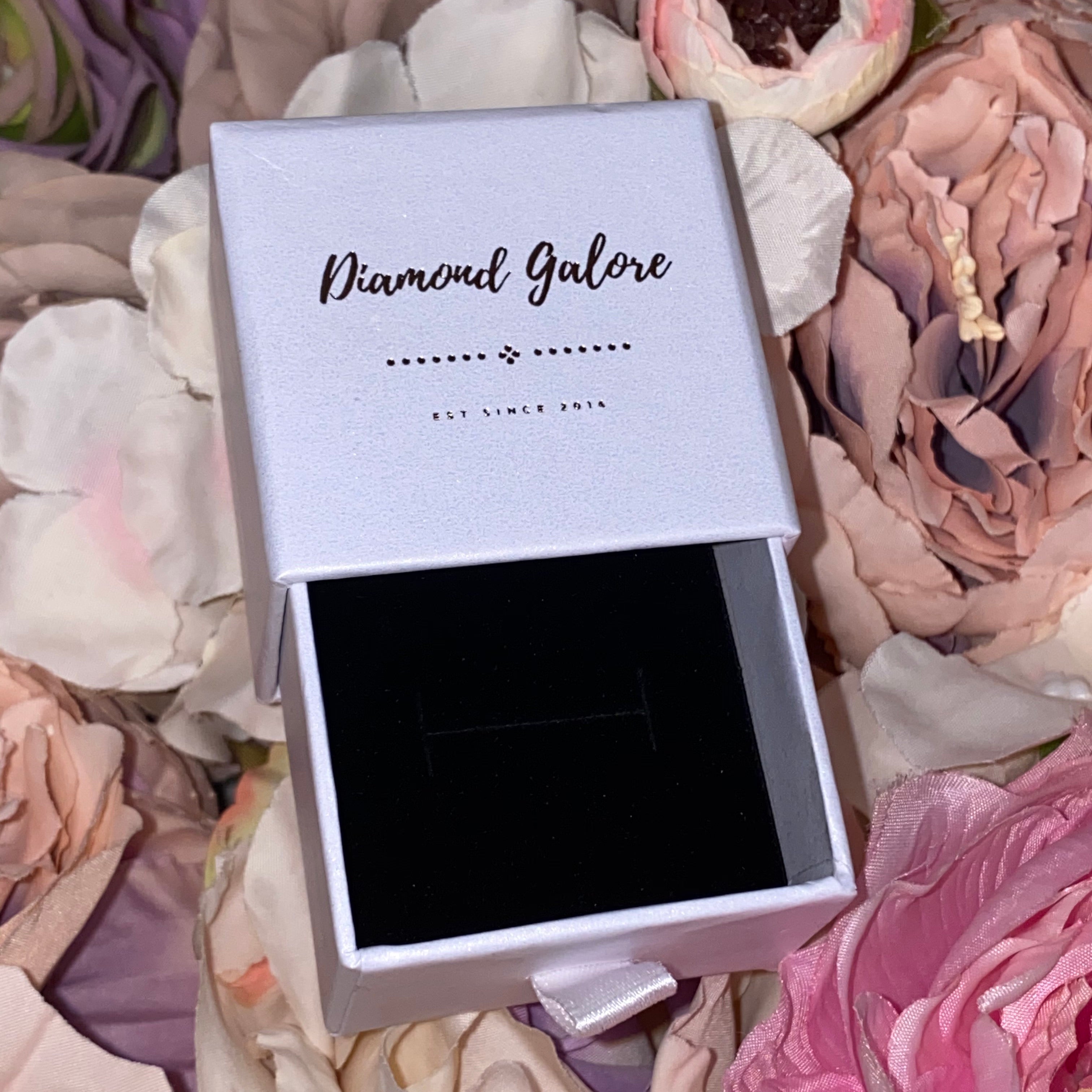 A white jewellery box with a velvet-style insert, branded 'Diamond Galore', displayed on a floral background.