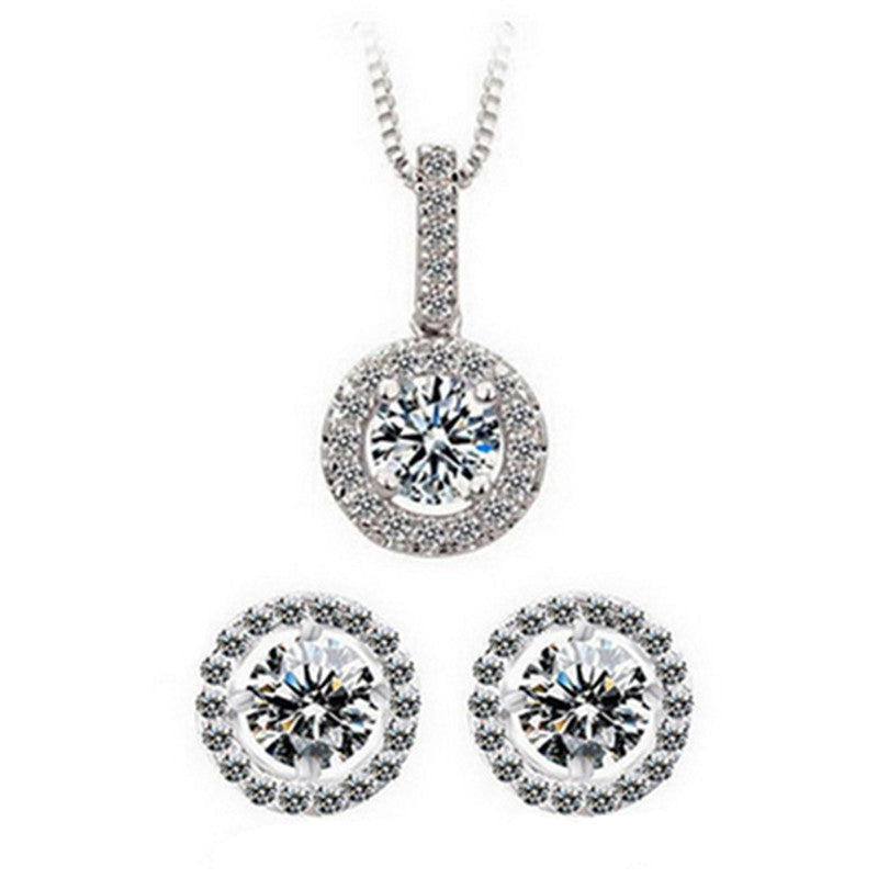 A set of sterling silver jewelry including a round pendant necklace and a pair of stud earrings, with intricate designs and sparkling stones.