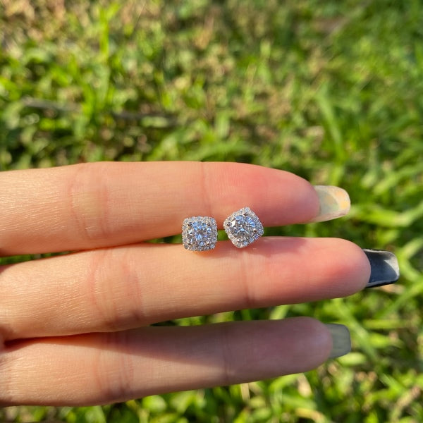 A pair of mini square studs with a round main stone in a silver setting.