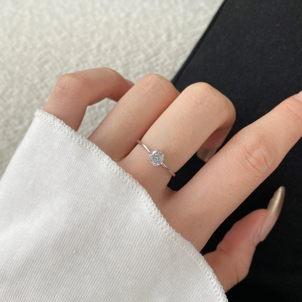 A silver-colored adjustable ring featuring a round 0.5 ct zirconia main stone set in a silver-colored band.