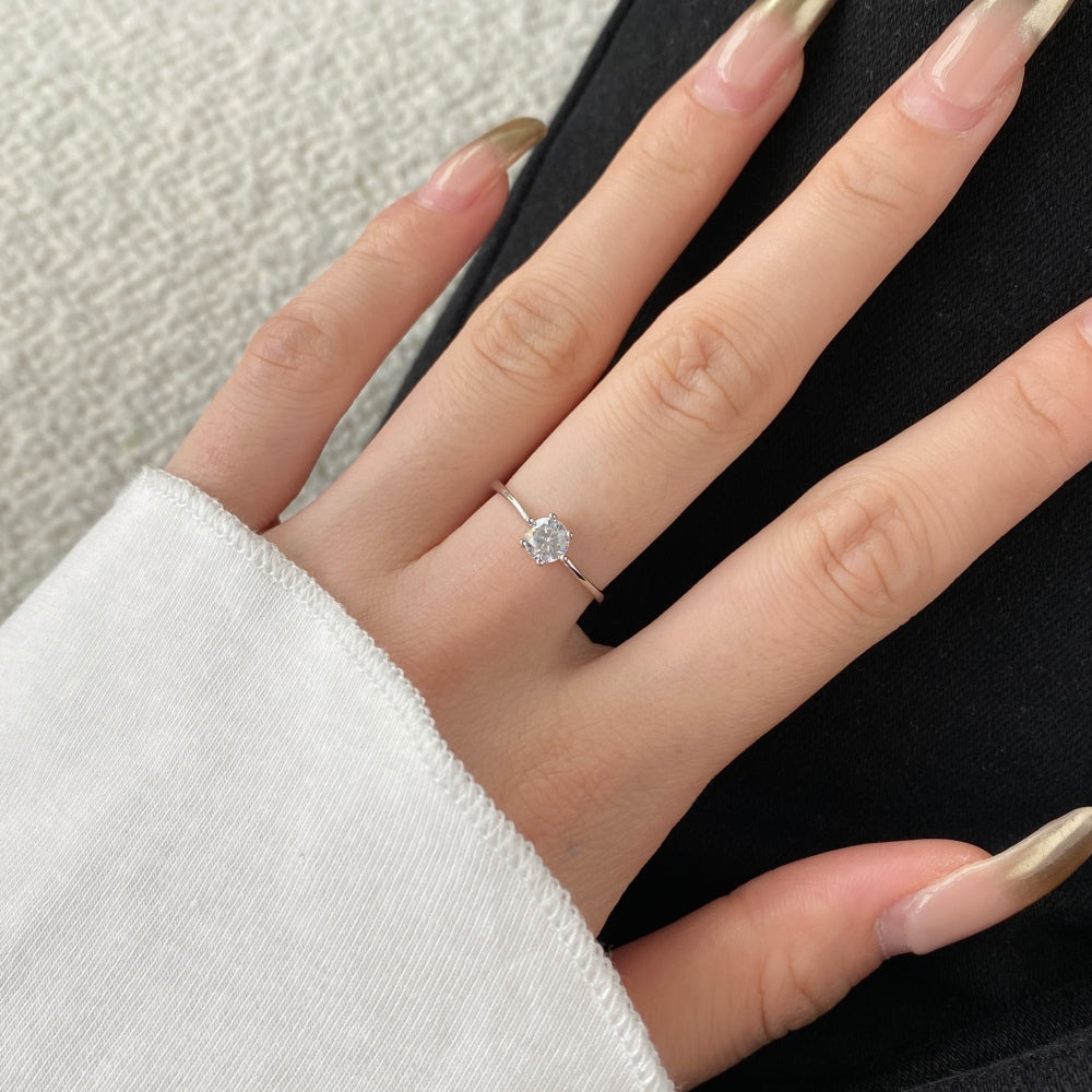 A silver-colored adjustable ring featuring a round 0.5 ct zirconia main stone set in a silver-colored band.