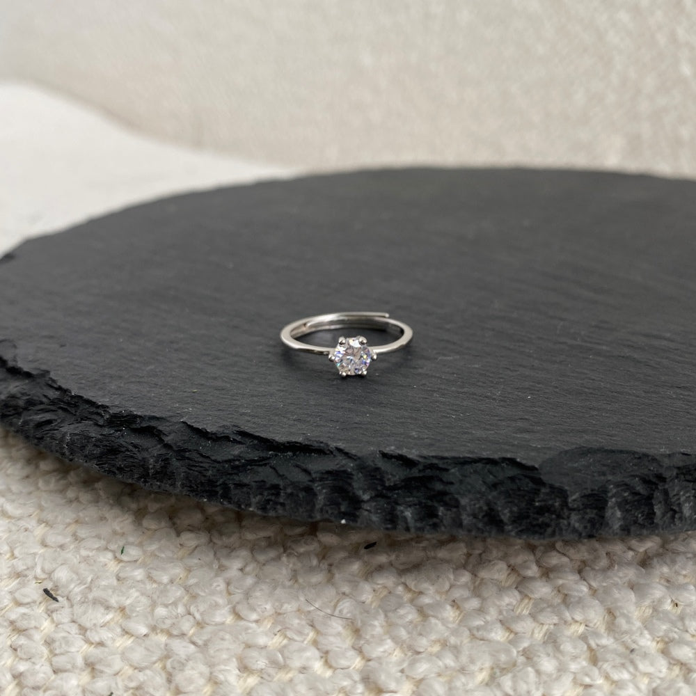 A silver-colored adjustable ring featuring a round 0.5 ct zirconia main stone set in a silver-colored band.
