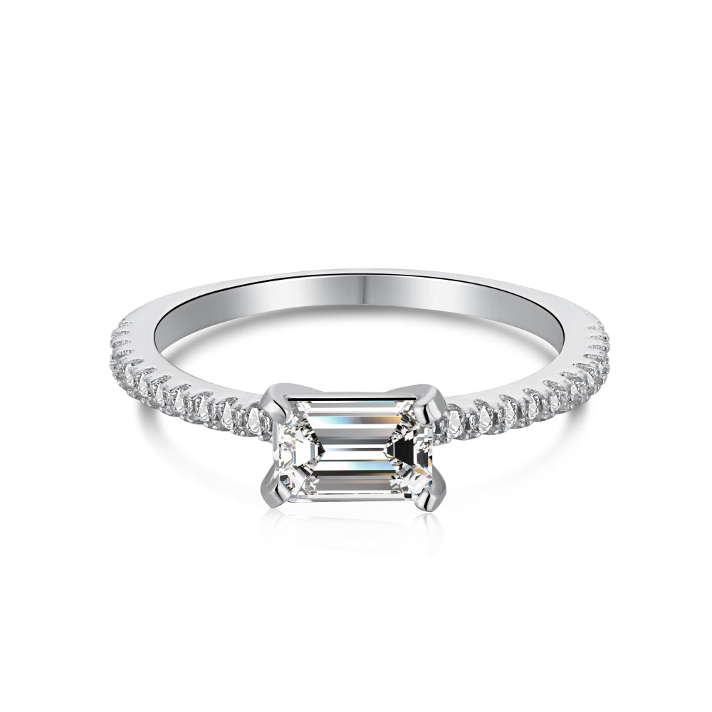 A silver ring featuring a rectangular emerald cut main stone with a surrounding diamond-accented band.