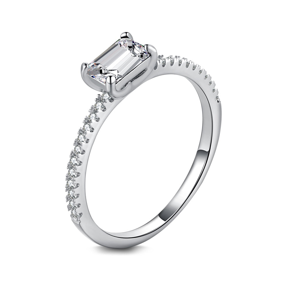 A silver ring featuring a rectangular emerald cut main stone with a surrounding diamond-accented band.