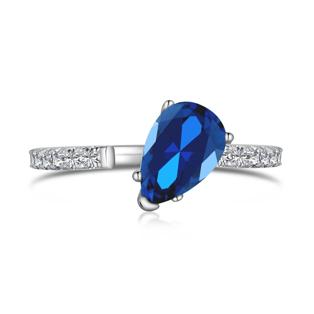 A blue pear-shaped zircon ring with a white silver band and small clear crystals set around the top edge.