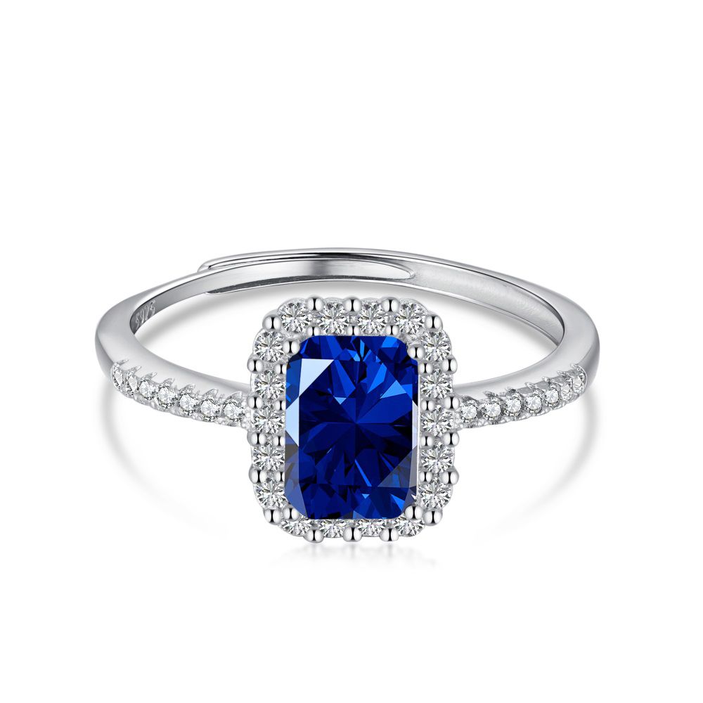 A rectangular-shaped royal blue sapphire ring with a metallic band and small clear stones set around it.
